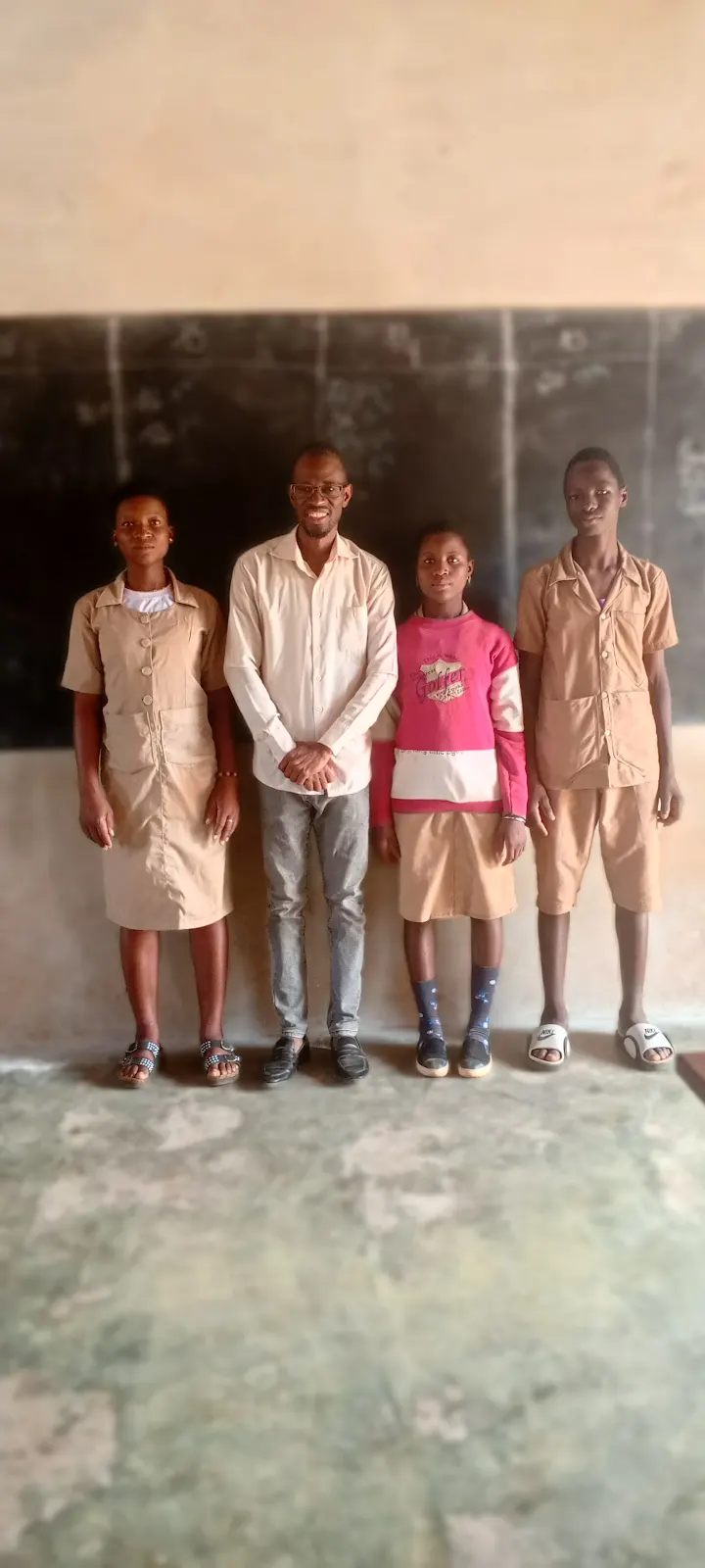Coach Sika standing with students in a classroom